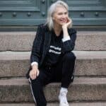 Eldre kvinne sitter på trapp og smiler